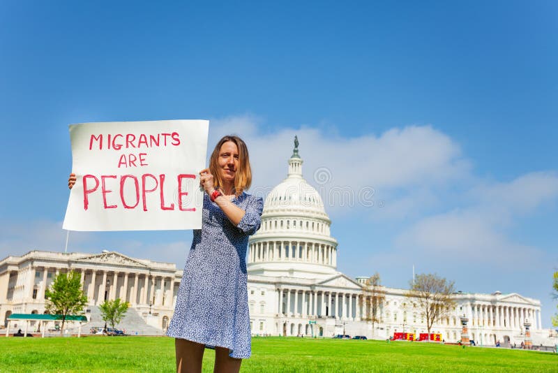 Woman protest in front of the USA capitol in Washington holding sign saying migrants are people. Woman protest in front of the USA capitol in Washington holding sign saying migrants are people